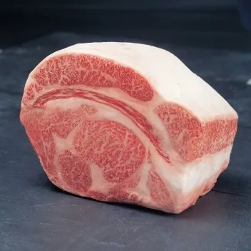 A raw, thick cut of premium Japanese Miyazaki Wagyu beef steak showcasing its world-renowned, intricate white marbling against a dark slate background.